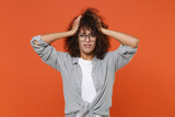 Fototapeta Nowy Jork - Preoccupied displeased young african american woman girl in gray casual clothes, eyeglasses isolated on orange wall background studio. People lifestyle concept. Mock up copy space. Put hands on head.