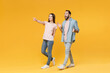 © ViDi Studio - Excited young couple two friends guy girl in pastel blue casual clothes posing isolated on yellow background. People lifestyle concept. Mock up copy space. Pointing index finger aside spreading hands.