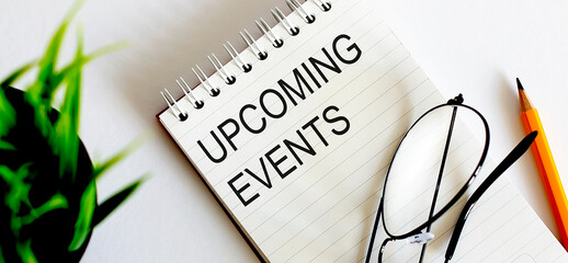 Poster - Notebook with glasses and pencil on wooden table, business concept. Text UPCOMING EVENTS