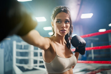 Wall Mural - Female boxer showing hit in boxing gloves.