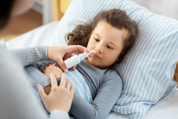 Sticker - family, health and medicine concept - mother with nasal spray treats little sick daughter lying in bed at home