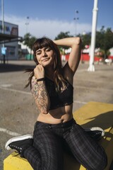 Sticker - Young attractive Caucasian female with tattoos sitting in the street and making a cute face