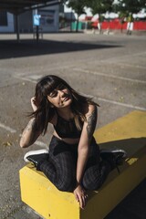 Poster - Young attractive Caucasian female with tattoos sitting in the street and making a cute face