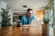 © bnenin - Handsome man taking notes and looking at laptop, at home office, portrait.
