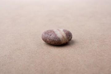 Canvas Print - Closeup of a single pebble stone isolated on a beige background