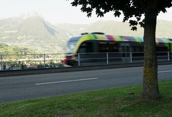 Canvas Print - Blurred moving regional colorful train in Meran city