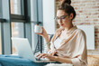 © Drobot Dean - Image of focused woman working with laptop and drinking coffee