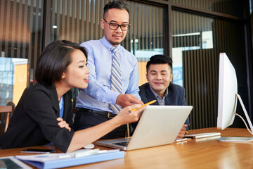 Group of modern business people spending time together at office desk coworking on new project using latop