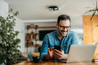 © bnenin - Portrait of a happy man with smart phone and laptop, indoors.