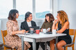 © unai - Session young entrepreneurs in the office, a young man of Latin ethnicity and three young Caucasian women sitting at a table in the office one summer morning