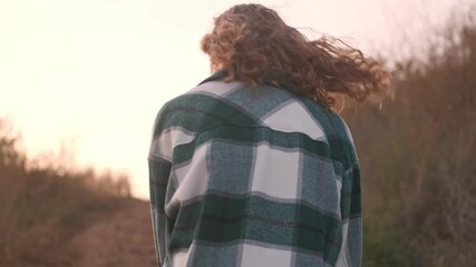 Sticker - Back view of pleased blonde woman wearing plaid shirt walking near the sea outdoors