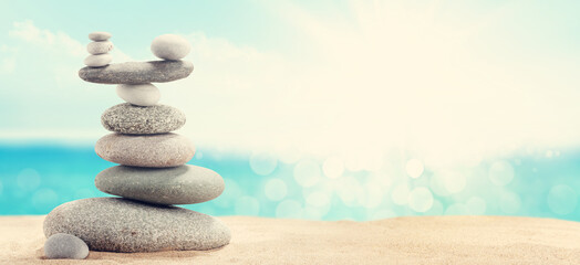 Pyramid of sea pebbles on a sunny sand beach