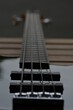 Das Griffbrett einer schwarze E Bass Gitarre von unten fotografiert und auf dem Seitenhalter fokussiert. Man sieht die ganze länge der Seiten und des Griffbretts und ein Teil des Korpus.