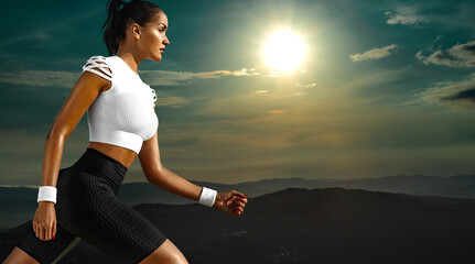 Wall Mural - Sporty young woman and fit athlete runner running on the sky background in the mountains. The concept of a healthy lifestyle and sport. Woman in black and white sportswear.