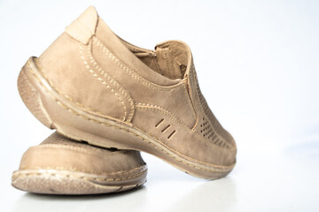 Men's beige leather shoes, models moccasins. Photographed close-up on a light background.