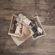 Old Vintage Monochrome Photographs In Sepia Color Are Scattered On A Wooden Table, The Concept Of Genealogy, The Memory Of Ancestors, Family Ties, Memories Of Childhood