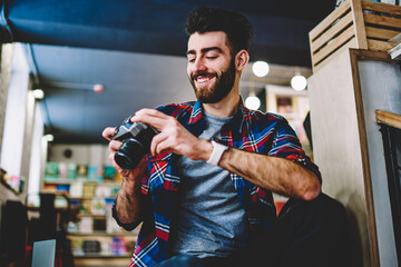 Portrait of handsome hipster photographer dressed in casual shirt smiling at camera.