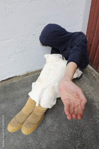 Fotomural homeless man with hooded sweatshirt and old oversized boots asks