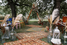 Visiting Wedding Ceremony In Boho Style. Triangular Wooden Arch Decorated With Flowers.