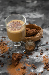 a cookie with pieces of chocolate tied with a string lies on a wooden board and next to a cup of latte