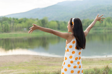 Asian beautiful young woman is happy and spreading arms and watching the mountain and river enjoying and relaxing to natural scenery.