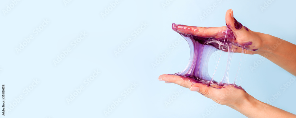 Young girl hands with sticky purple slime on blue background, liquid wax for depilation, conceptual flyer banner with copy space, antistress relax, modern kids hobby oddly satisfying semi surreal asmr - obrazy, fototapety, plakaty 