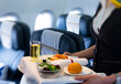 © Aureliy - flight attendant serving meal in an airplane
