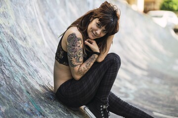 Sticker - Young attractive Caucasian female with tattoos sitting on a skating ramp