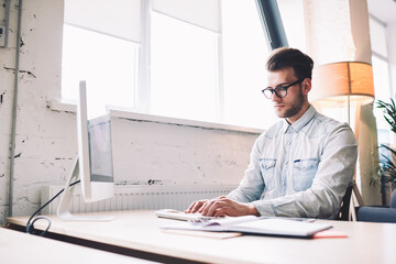 Poster - Serious male software developer keyboarding program code on modern computer sitting at desktop, caucasian skilled man working with technology connected to wireless internet while typing email