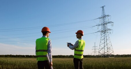 Wall Mural - two power engineers meet near power lines and discuss reconstruction of high-voltage lines on a pape
