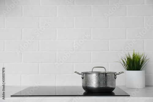 Fotografía Saucepot on induction stove in kitchen, space for text