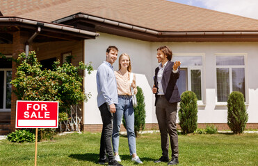 House agent talking to young couple about residential property purchase in backyard