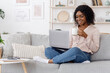 © Prostock-studio - Leisure Concept. Young woman relaxing at home on the couch, having coffee and using laptop computer, copyspace