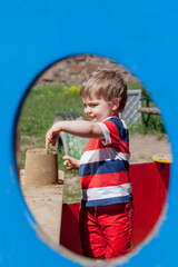 Poster -  boy in a colored T-shirt plays in the sandbox