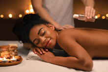 Relaxed African Woman Enjoying Aromatherapy And Massage At Spa