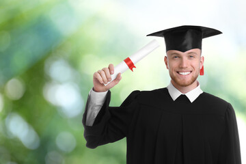 Wall Mural - Happy student with graduation hat and diploma on blurred background, space for text