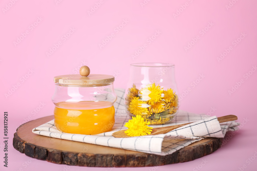 Jar of dandelion honey on color background