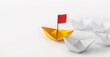 Leadership concept. Red flag Origami Yellow Paper boat (ship) leading the other white boats.  One leadership leads other ships.
