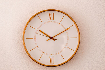 Gold clock on the wall on a homogeneous background