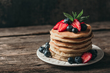 Wall Mural - American pancakes with fresh berry on wood background. Summer homemade breakfast.