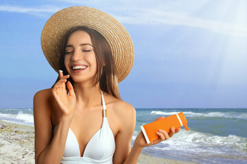 Poster - Young woman applying sun protection cream at beach