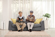 © Ljupco Smokovski - Elderly men sitting on a sofa and reading books in a living room