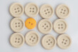 © Ahmad - A single out yellow button among white buttons,shot from top over a clear white surface