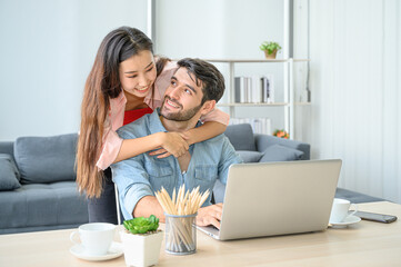 Happy and relax  lifestyle of young couple lover wearing casual dress together working on laptop notebook computer in living room at home.