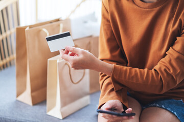 Closeup image of a woman holding credit card with shopping bags at home for online shopping concept