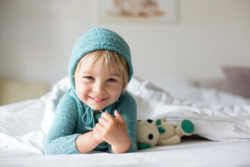 Canvas Print - Cute toddler boy with handmade knitted toy, lying in bed