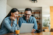 © bnenin - Cute couple relaxing at home, using laptop and sitting at table.