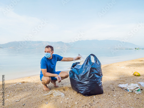 Man in gloves pick up plastic bags that pollute sea. Problem of spilled rubbish trash garbage on the beach sand caused by man-made pollution, campaign to clean volunteer in concept