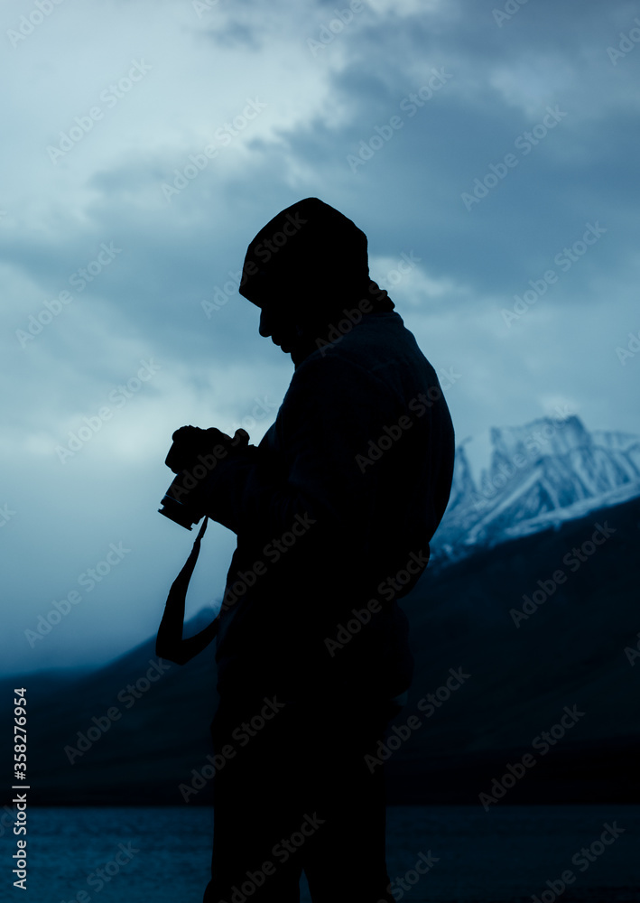 silhouette of a man with a camera in the cold mountainous region of ...