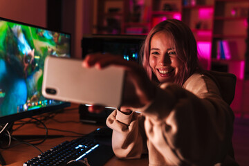 Poster - Image of girl taking selfie on cellphone while playing video game